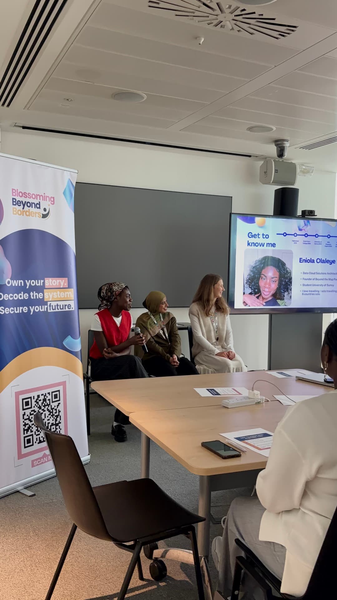 A panel session in front of the screen and Blossoming Beyond Borders banner at the Microsoft Insight Day